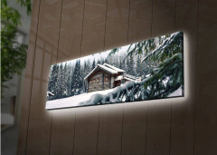 Canvastavla med LED-belysning 30x90 cm - Vinterlandskap med en stuga omgiven av snö och granar - Vit / Grön / Brun
